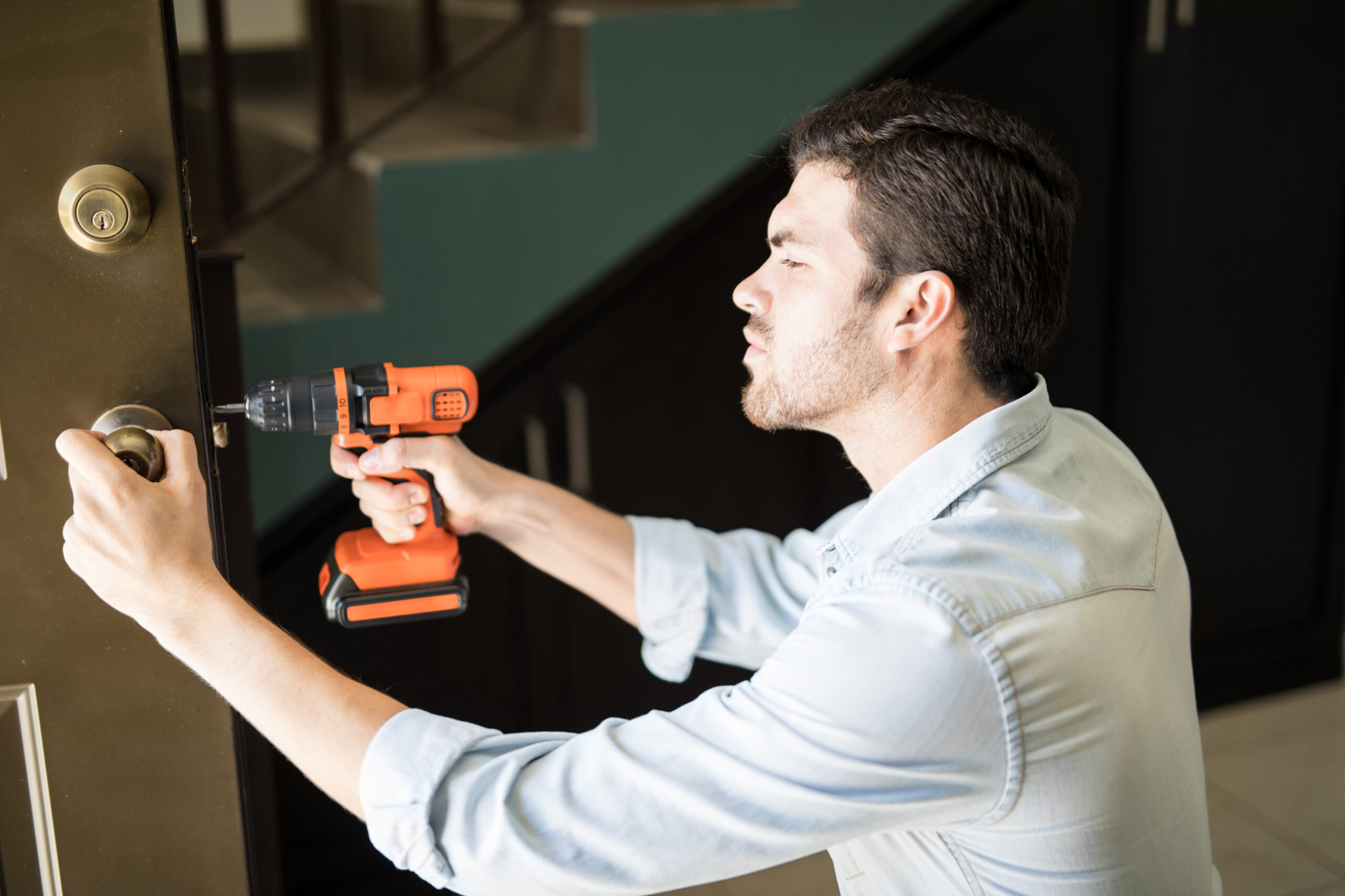 Handyman installing a door knob with a power drill